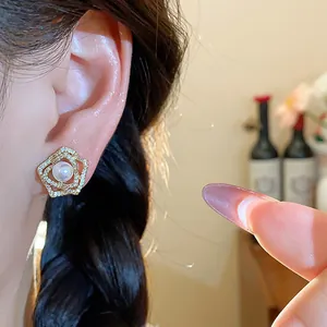 Close-up of elegant 14k gold plated pearl flower earring with sparkling rhinestones.