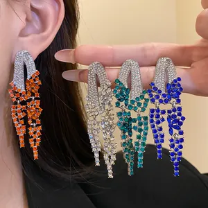 Macro detail of elegant geometric tassel earrings featuring colorful sparkling rhinestones