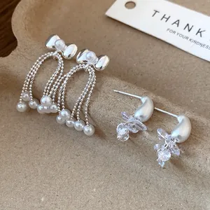 Detailed view of silver bow pearl tassel earrings and frosted pearl crystal studs