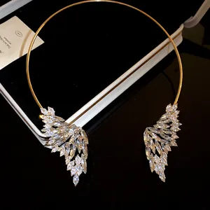 Dettaglio ravvicinato delle ali di cristallo su questa elegante collana in metallo oro.