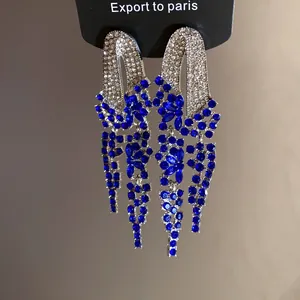 Macro detail of elegant silver-toned tassel earrings adorned with blue and white rhinestones