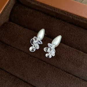 Detailed view of pearl and crystal stud earrings resting in a brown velvet jewelry box.