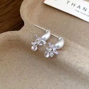 Close-up of elegant silver needle earrings with matte teardrop and crystals
