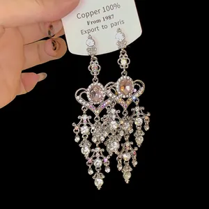 Close-up of elegant silver tassel earrings with pink gemstones on a white card