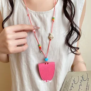 Chic pink leather sunglass holder necklace with colorful beads and shell charms.
