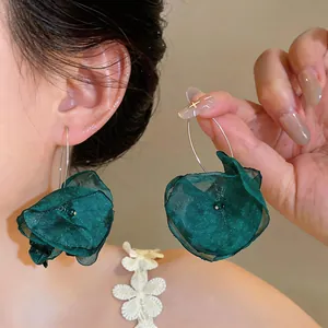 Elegante smaragdgrüne Chiffon-Blumen-Creolen, an Model in Nahaufnahme gezeigt