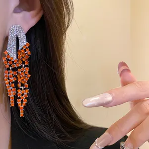 Detailed close-up of vintage geometric tassel earrings with orange and clear rhinestones