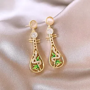 Detailed view of gold Pipa earrings with cat's eye stone and green bamboo leaf accents.