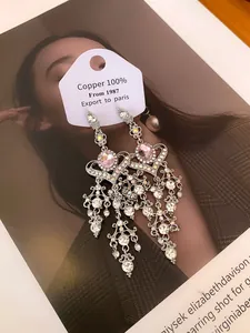 Detailed view of ornate silver heart tassel earrings with pink crystals and rhinestones