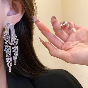 Detailed view of elegant silver needle tassel earrings with shimmering rhinestones on ear