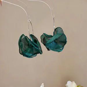 Detailaufnahme von dunkelgrünen Chiffon-Blütenohrringen an transparenten Haltern.