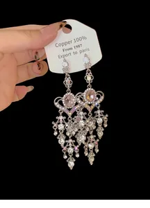 Detailed macro view of silver needle tassel earrings with sparkling rhinestones and heart design