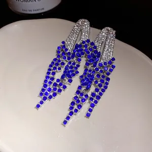 Close-up detail of luxurious silver-plated earrings featuring vibrant blue rhinestone tassels