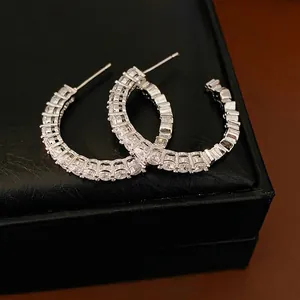 Elegant silver C-shaped hoop earrings with sparkling zircon stones on a black gift box.
