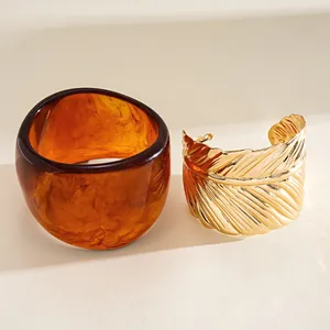 Detail view of amber resin geometric bracelet and golden feather textured cuff jewelry