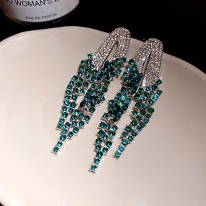 Macro detail of elegant green rhinestone geometric tassel drop earrings for women