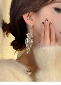 Close-up detail showing the sparkling rhinestone heart chandelier earrings on a model