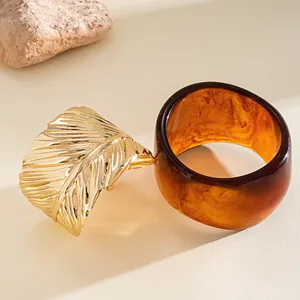 Detail view of gold leaf metal cuff and amber resin bangle jewelry set in warm light