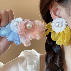 Close-up of elegant chiffon flower pearl earrings in yellow, blue and pink.