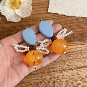 Orecchini artistici a fiocco di perle con resina blu e sfere arancioni traslucide