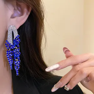 Close-up detail of luxury silver needle tassel earrings with elegant blue rhinestones