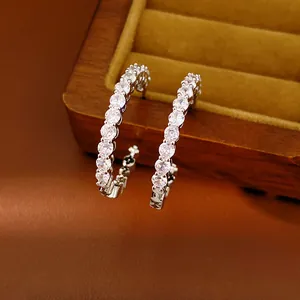 Detail view of elegant C-shaped hoop earrings encrusted with sparkling cubic zirconia stones.