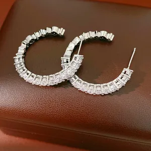 Close-up of elegant silver-needle C-shaped hoop earrings with sparkling cubic zirconia