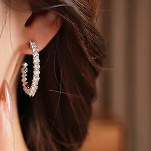 Detail view showing elegant C-shaped silver hoop earrings embellished with brilliant zircons