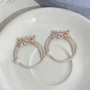 Luxury rhinestone hoop earrings with iridescent petals and pearls displayed on white plate