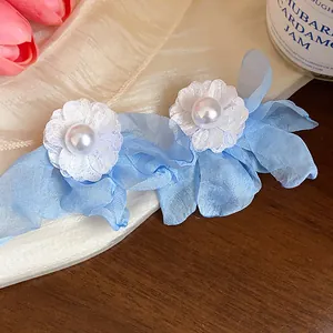 Detailed view of blue chiffon and white lace flower earrings with pearl center
