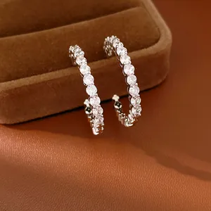 Close-up of elegant silver C-shaped earrings with sparkling round zircons in detail.