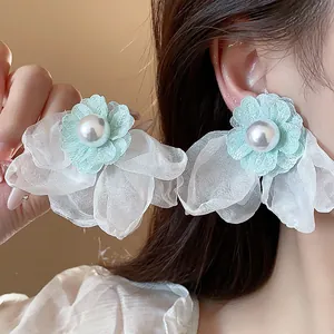 Close-up of elegant mint green chiffon flower earrings with pearl centers on model