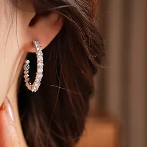 Detailed view of silver-toned zircon-studded C-shaped hoop earring on model's ear