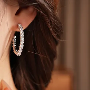 Close-up detail of silver C-shaped hoop earrings set with sparkling round cubic zirconia