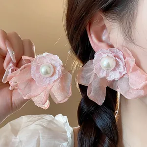 Detailed view of elegant pink chiffon flower earrings with central pearl on a model