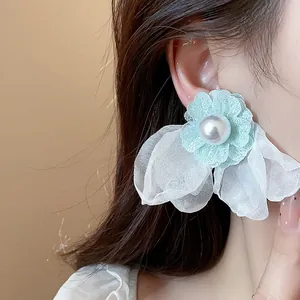 Macro detail of elegant mint green chiffon flower pearl earring worn on female ear model