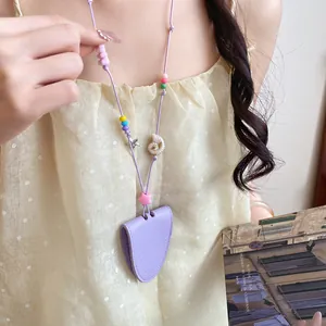 Detail view of a purple leather sunglasses clip necklace with shell and colorful bead charms.