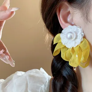 Close-up detail of a chiffon flower earring with a central pearl on a model's ear