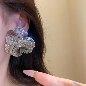 Detail shot of elegant silver brushed metal flower earring with central pearl