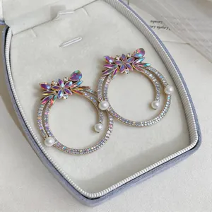 Close-up of luxury oversized hoop earrings with iridescent crystals and pearls