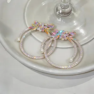 Close-up of rhinestone flower hoop earrings with drop pearls and colorful crystals