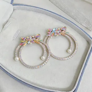 Close-up of luxury crystal hoop earrings with iridescent butterfly and pearl detail