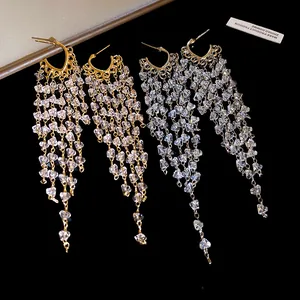 Vue détaillée des glands en cristal scintillant sur boucles d'oreilles or et argent.