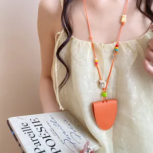 Detail of orange leather glasses holder necklace with vibrant beads and shell charms.
