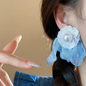 Detailed view of elegant blue chiffon floral stud earrings with white pearl center