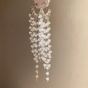 Gros plan d'élégantes boucles d'oreilles argentées à glands avec cristaux brillants.
