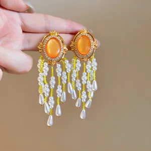 Elegante Ohrringe mit orangefarbenem Edelstein und weißen Perlen-Quasten-Anhängern.