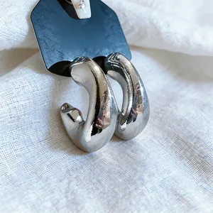 Macro detail of minimalist chunky silver C-shaped hoop earrings with mirror finish