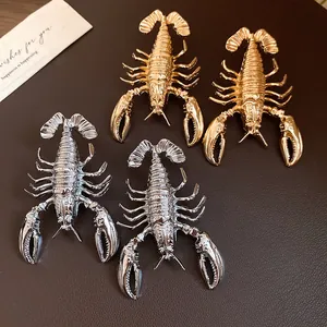 Detailed macro view of vintage gold and silver lobster earrings on a leather surface