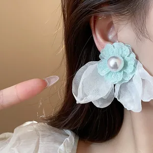 Close-up of elegant light blue chiffon flower earring featuring a central pearl detail